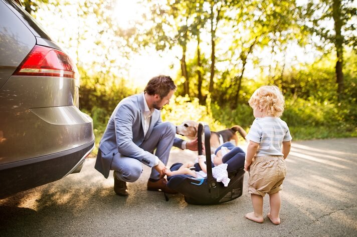 young-father-with-baby-and-toddler-by-the-car