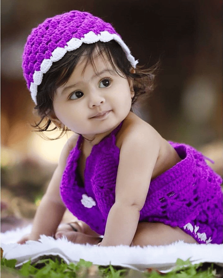 A baby wearing a violet knitted outfit 