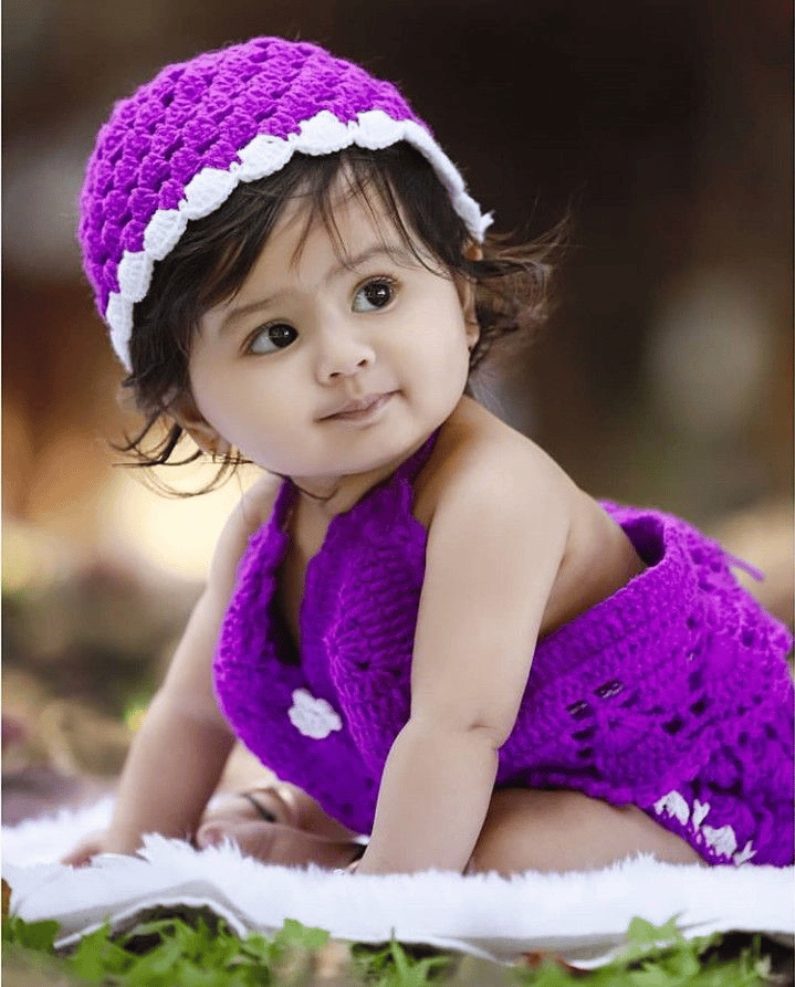 A baby wearing a violet knitted outfit A baby wearing a violet knitted outfit