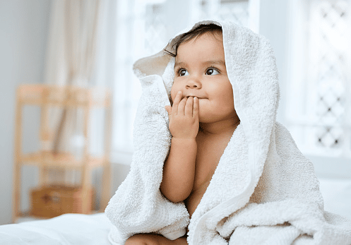 A baby wrapped in a blanket while staring upwards